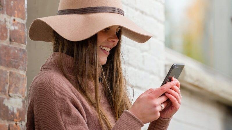 woman in brown hat and brown sweater holding smartphone