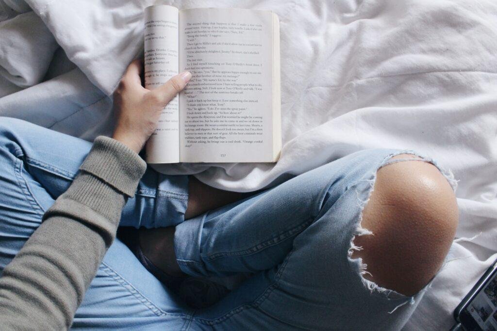 a girl is reading book sitting with cross legs
