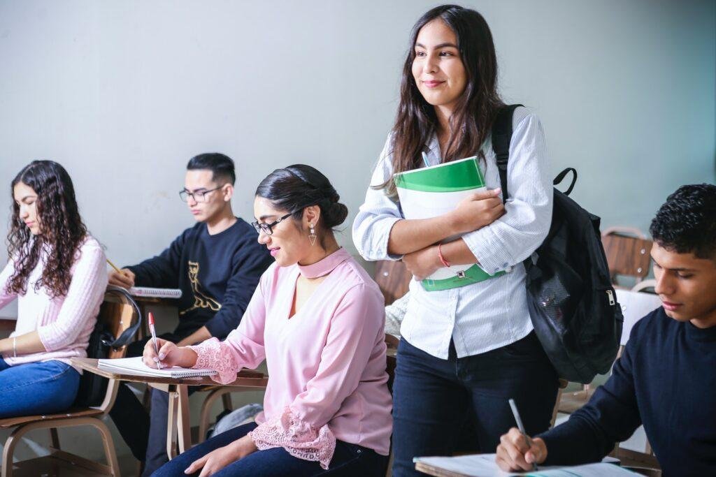 girl carrying white and green textbook