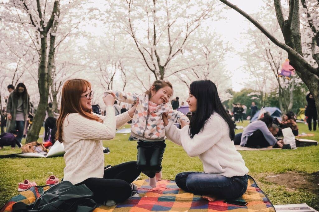 two women and a baby child is sitting in park