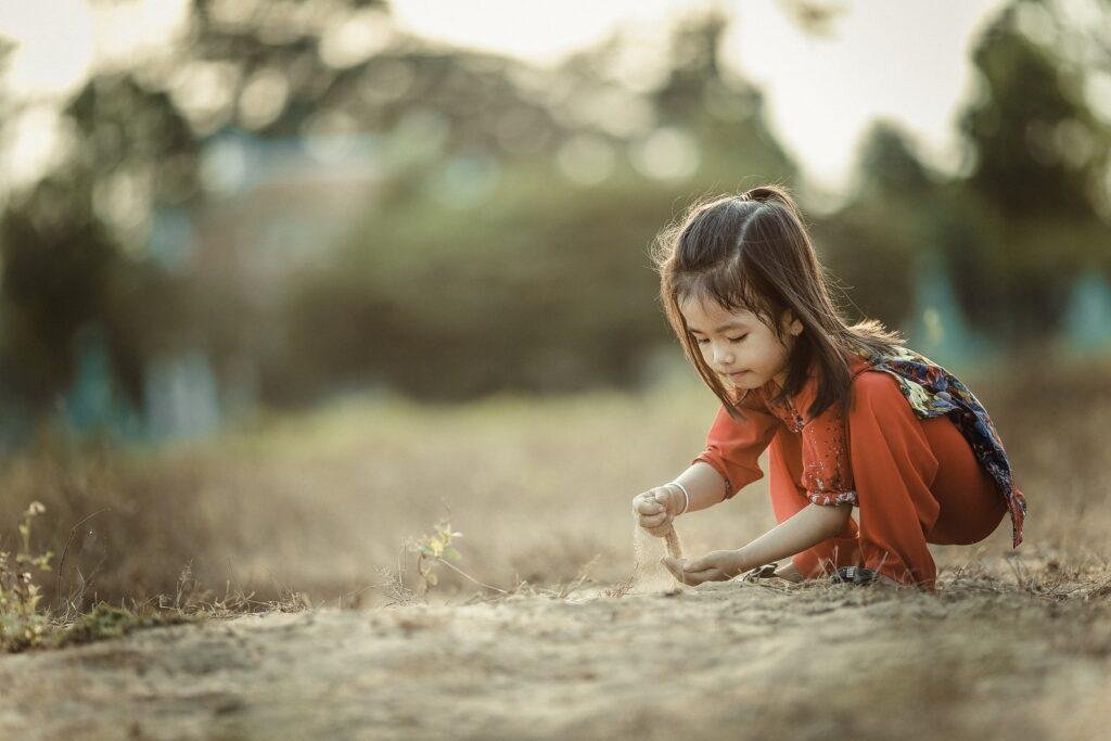 girl playing with sand in daytime