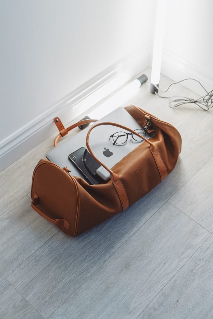 silver MacBook and phone in duffel bag
