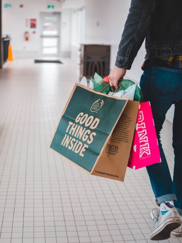 person walking while carrying a camera and paper bags