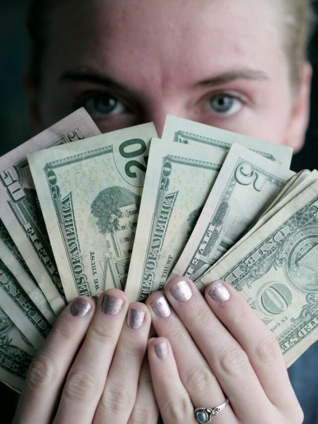 person holding fan of U.S. dollars banknote
