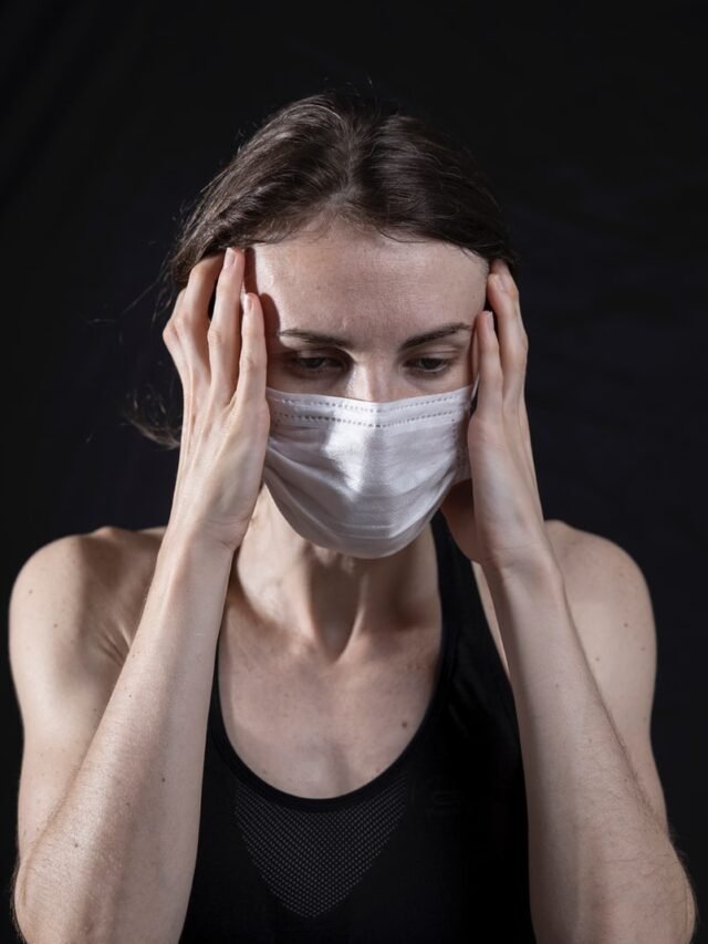 woman in black tank top covering her face with her hands
